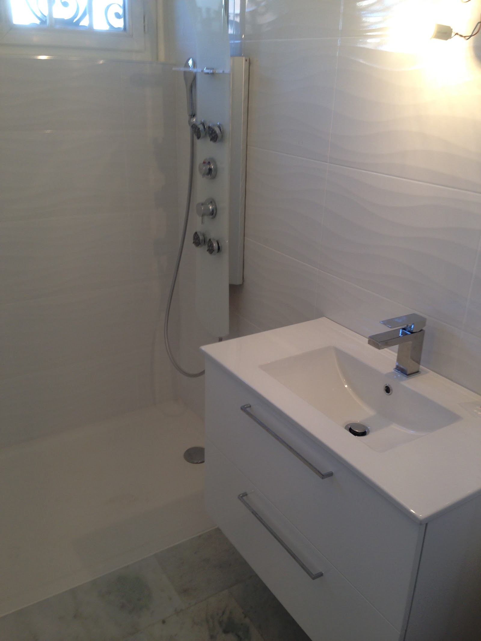 Zoom sur la vasque moderne et la colonne de douche hydromassante.
